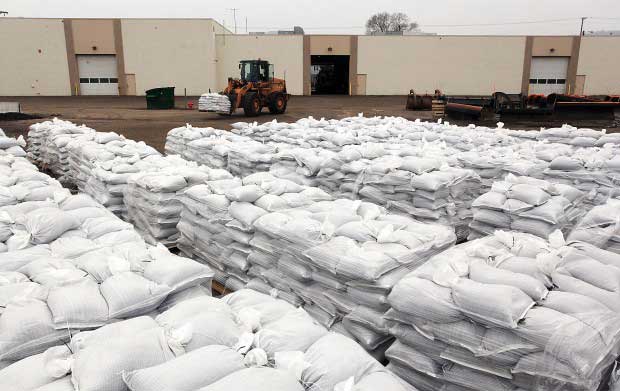 A large pile of filled sandbags neatly stacked inside a warehouse facility.