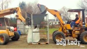 Two bulldozers operating a bulk bag filler machine to fill sandbags